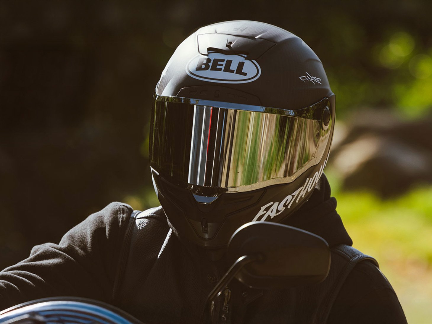 Rider wearing a Bell full-face motorcycle helmet with mirrored visor on a motorcycle